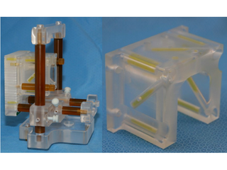 Biopsy template assembly (left) and Z-frame. MR-visible capsules are yellow within a plexiglass enclosure.